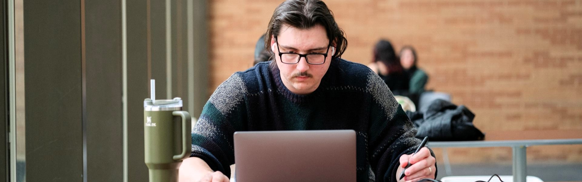 Man working on a laptop with a pen in his hand.